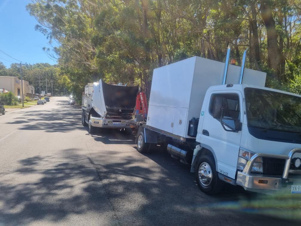 Two White Trucks Parked on a Sunlit Road — Mid North Coast Heavy Vehicle Repairs In Taree, NSW