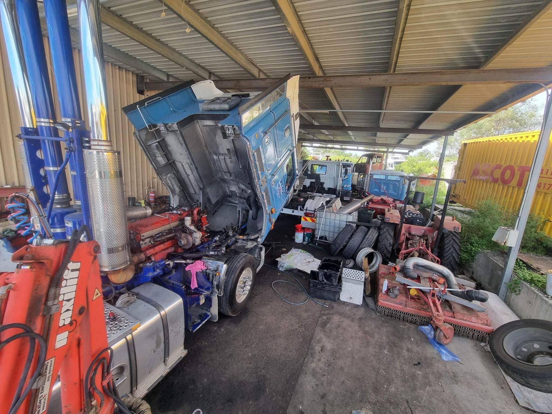 A Blue Semi-truck With Its Cab Tilted Forward for Repairs — Mid North Coast Heavy Vehicle Repairs In Bonny Hills, NSW