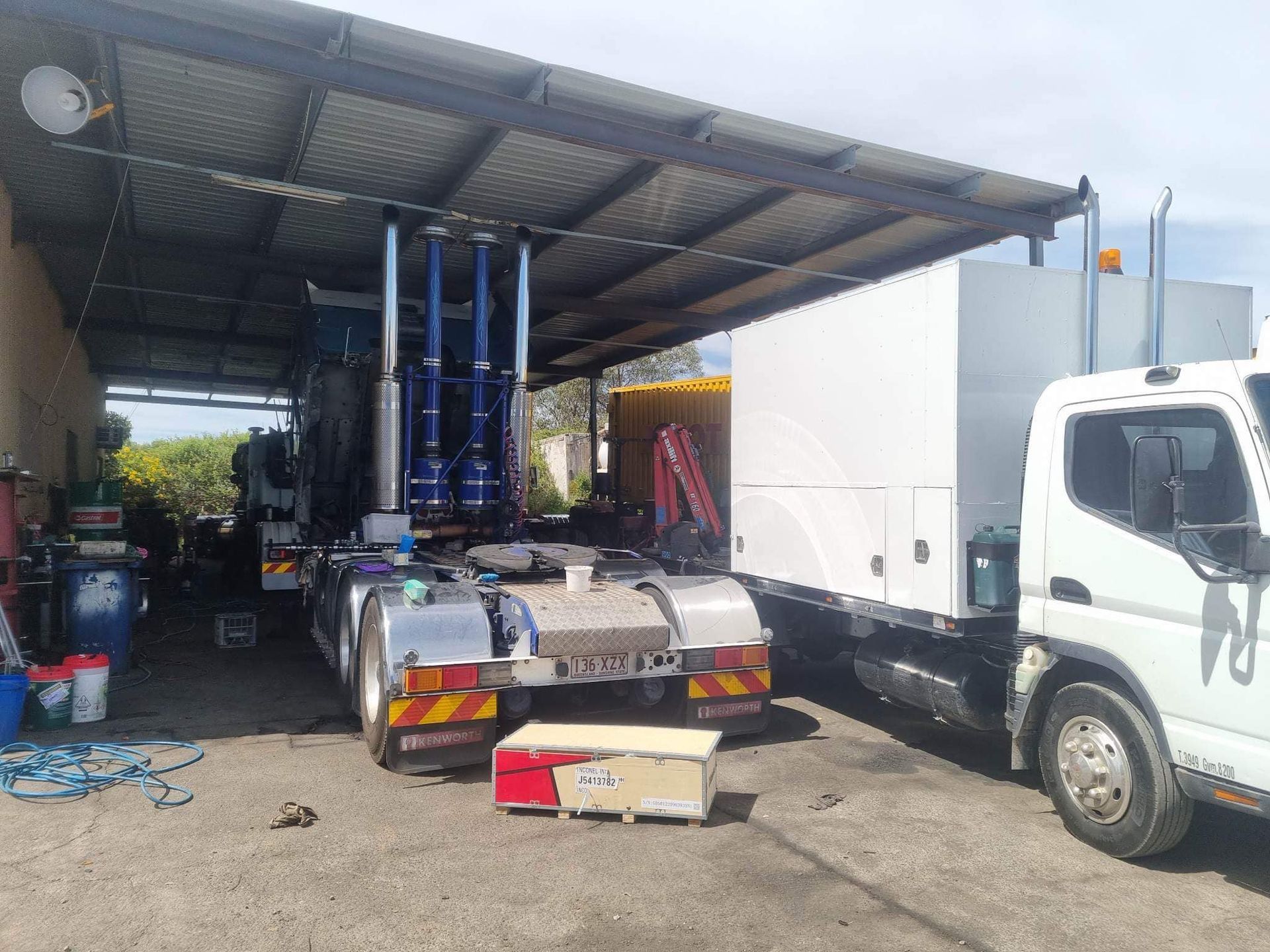 A White Truck and a Semi-truck Parked Under a Metal Canopy — Mid North Coast Heavy Vehicle Repairs In Taree, NSW
