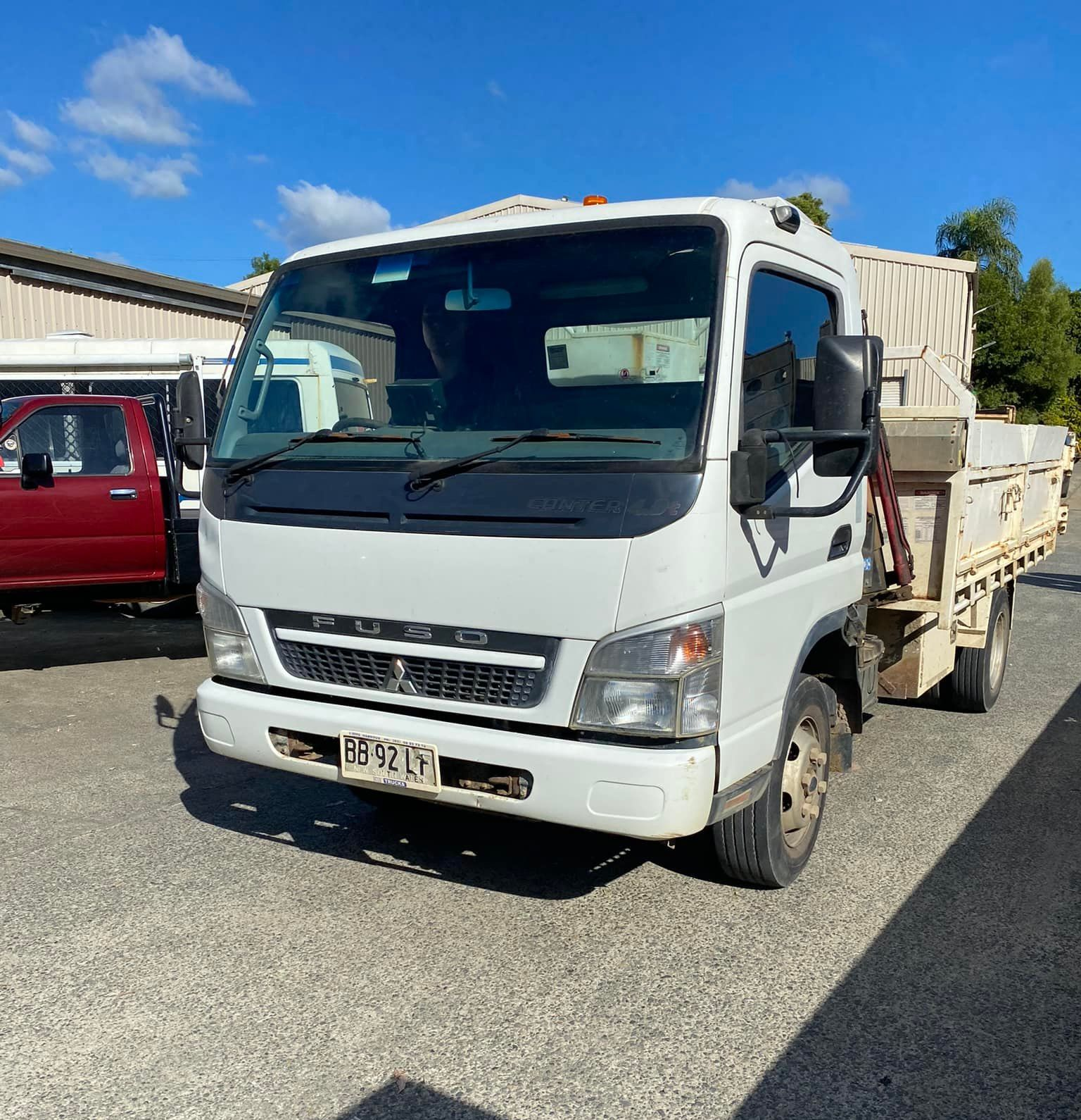 A White Mitsubishi Fuso Dump Truck Parked on a Gravel Lot — Mid North Coast Heavy Vehicle Repairs In Bonny Hills, NSW