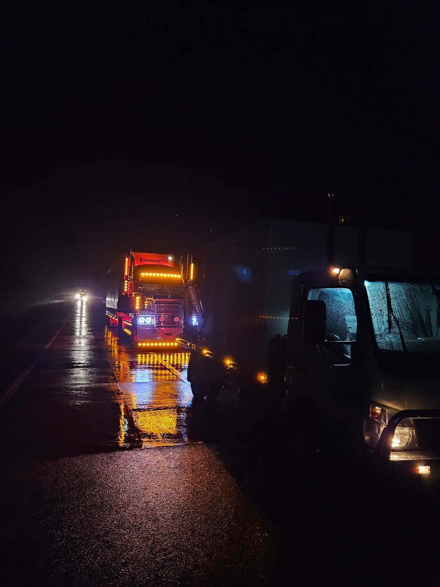 A Truck With Bright Orange Lights Parked on a Wet Road at Night — Mid North Coast Heavy Vehicle Repairs In Kempsey, NSW