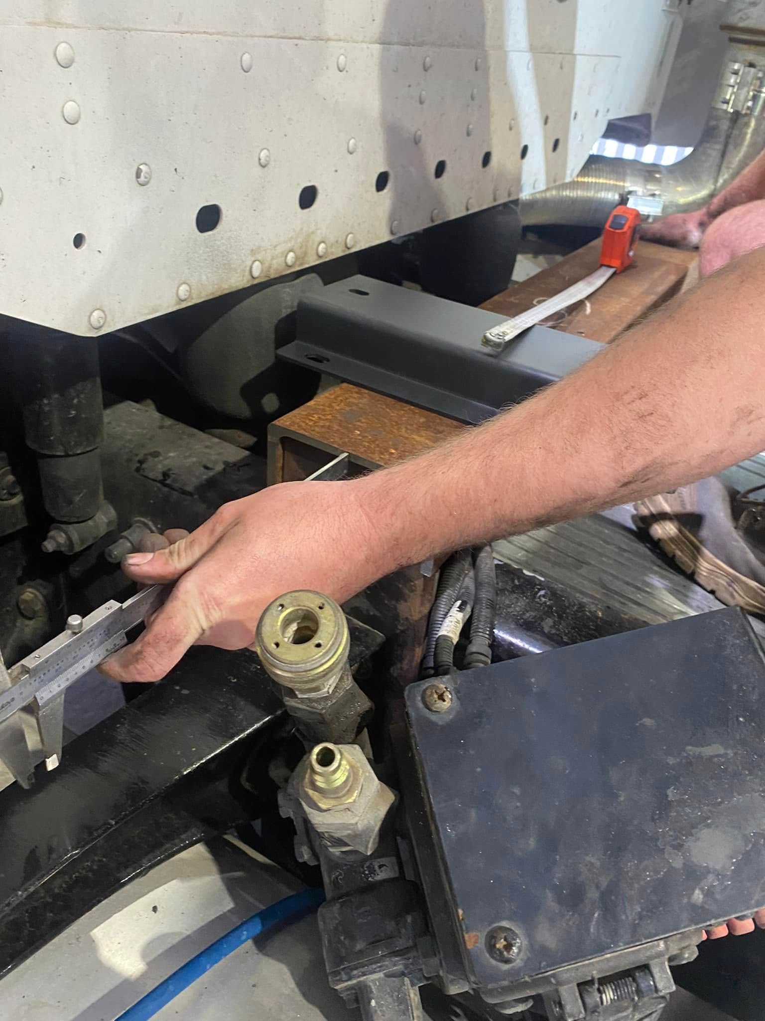 A Person Uses a Tape Measure to Measure a Metal Component — Mid North Coast Heavy Vehicle Repairs In Port Macquarie, NSW