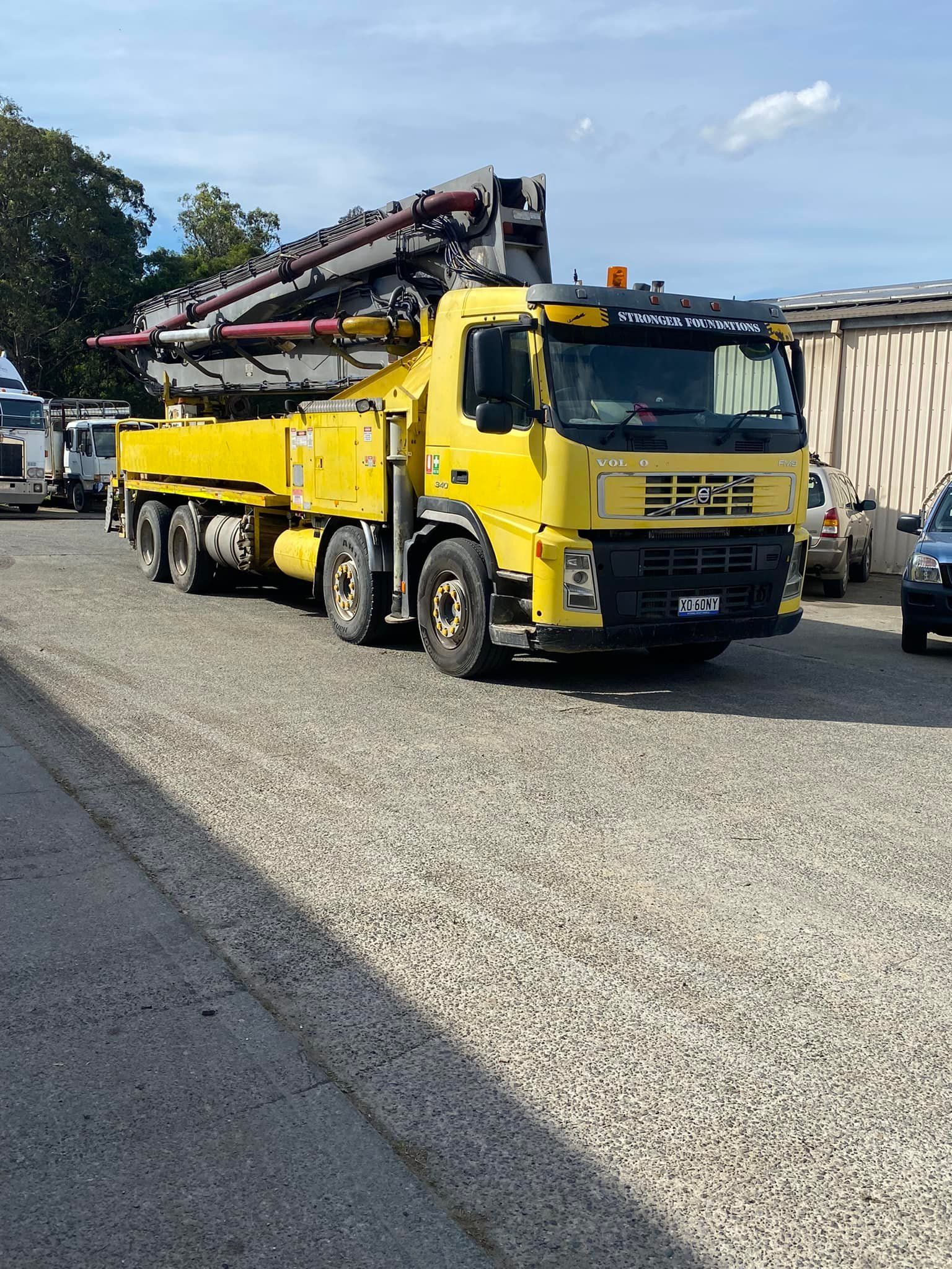 A Yellow Concrete Pump Truck Parked on a Gravel Lot — Mid North Coast Heavy Vehicle Repairs In Kempsey, NSW