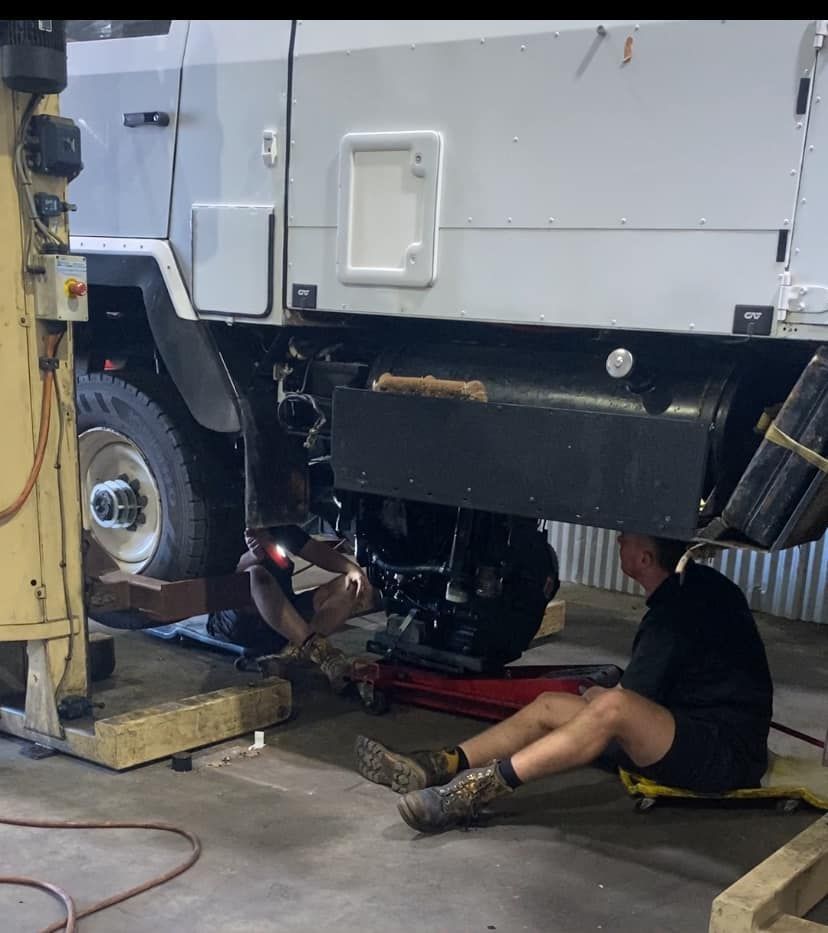 Two People Work Underneath the Lifted Chassis of a White Vehicle — Mid North Coast Heavy Vehicle Repairs In Wauchope, NSW