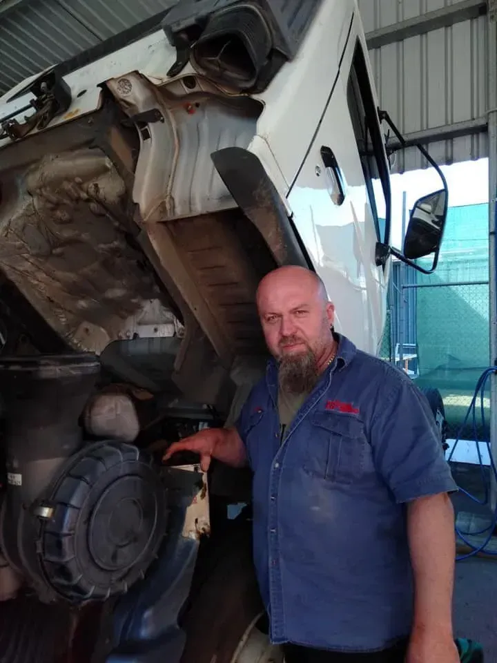 A Person in a Blue Work Shirt Stands Next to a Truck — Mid North Coast Heavy Vehicle Repairs In Wauchope, NSW
