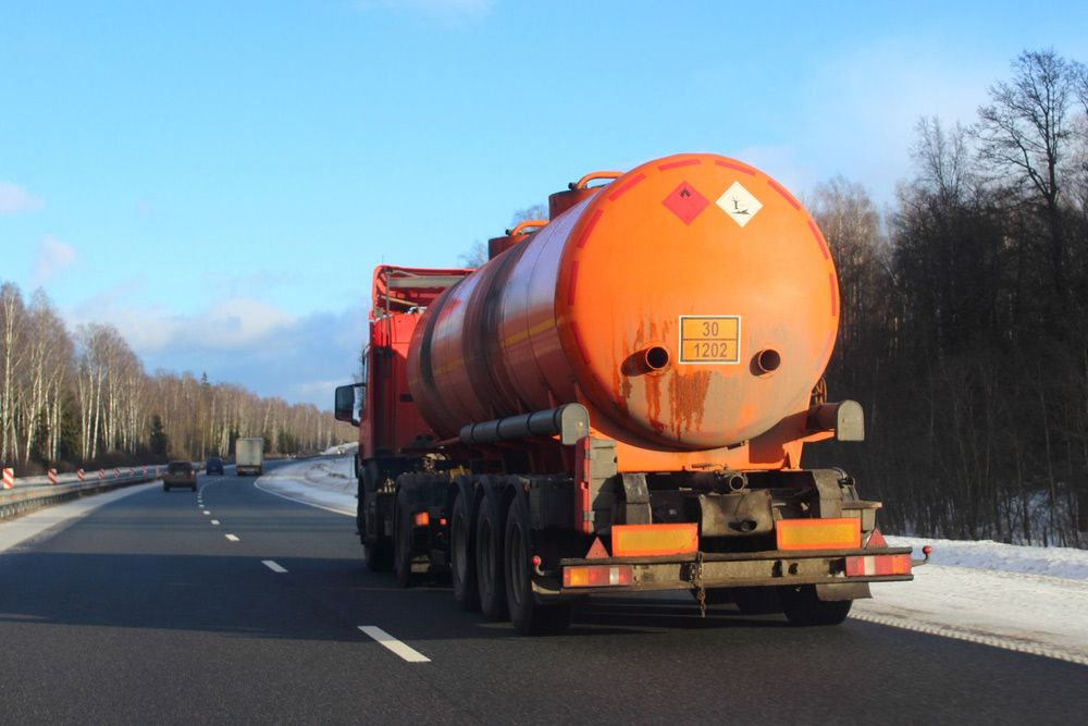 An Orange Fuel Tanker Truck Drives on a Road — Mid North Coast Heavy Vehicle Repairs In Thrumster, NSW