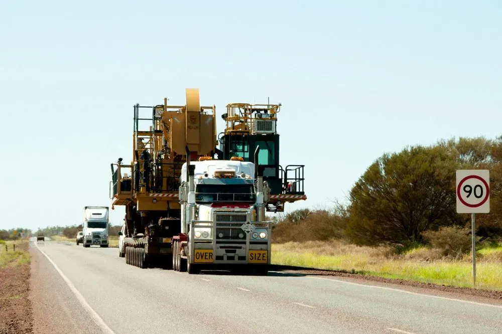 A White Semi-truck Transports Heavy Yellow Construction Machinery — Mid North Coast Heavy Vehicle Repairs In Thrumster, NSW