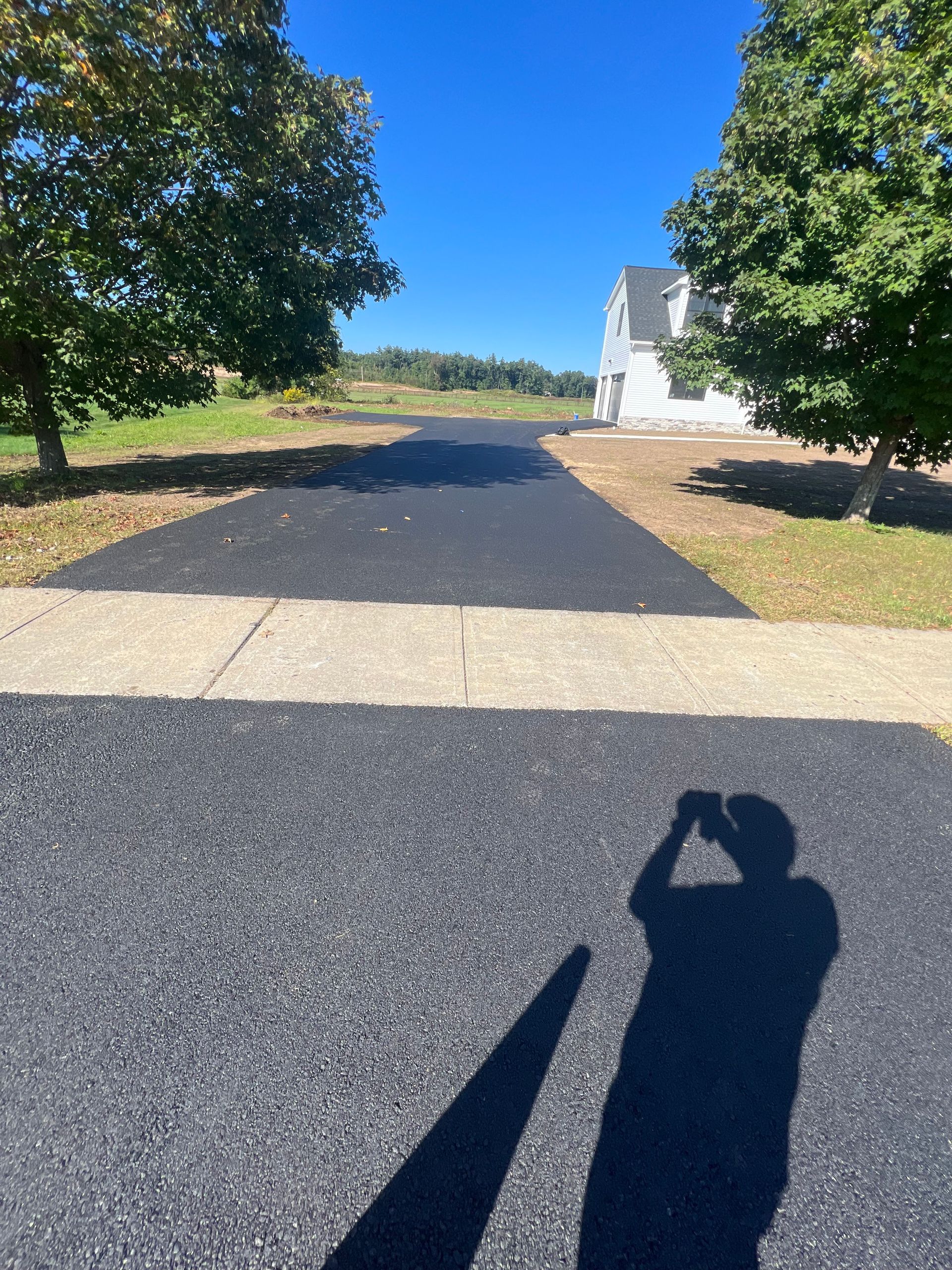 A person is taking a picture of their shadow on the road.