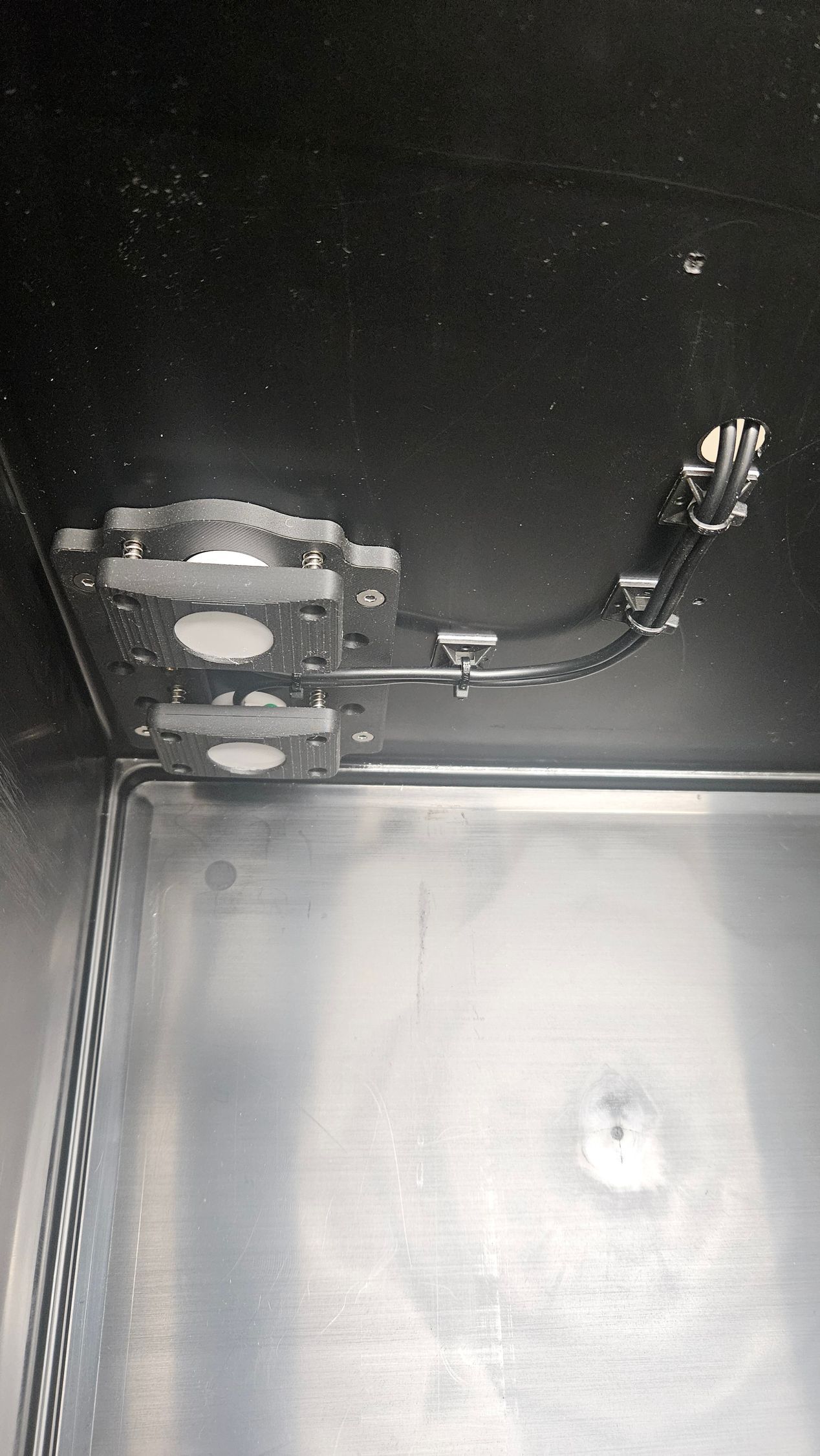 Im Inneren einer Trenntoilette mit metallischer Innenausstattung sind oben montierte Leuchten und Verkabelung sichtbar.
