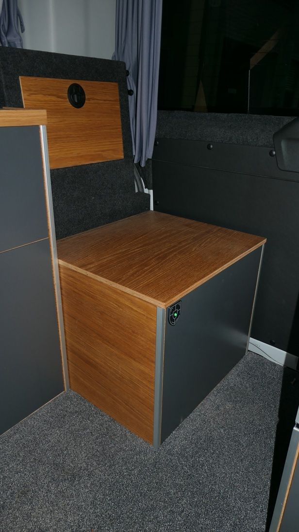 Holz- und graue Aufbewahrungseinheit mit Holzsitzbank in einem Lieferwagen.