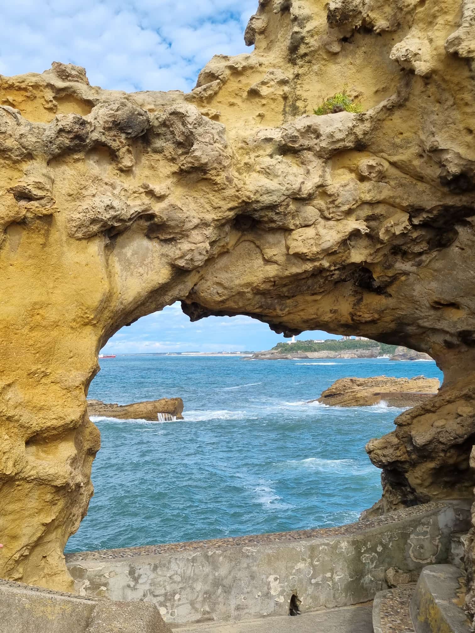 Meerblick durch einen natürlichen Felsbogen mit blauem Wasser und Himmel.