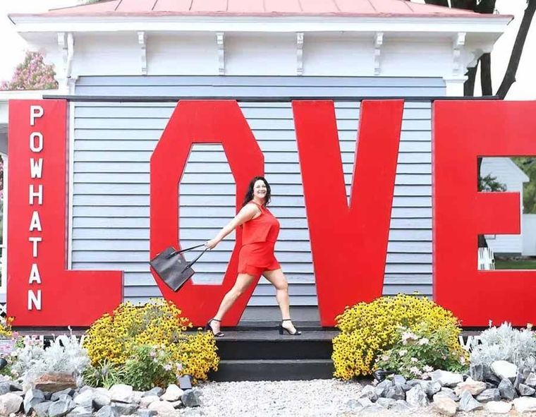 Woman in red posing in front of large red “LOVE” letters at Powhatan Point.
