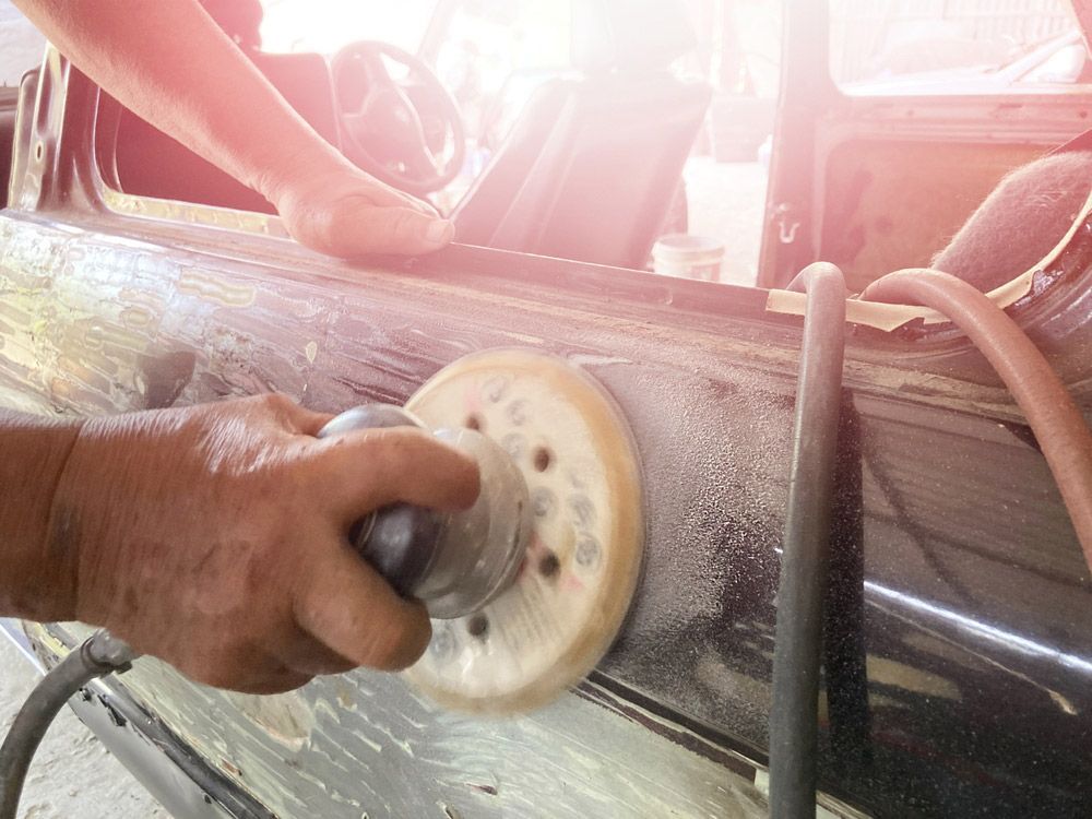 A Man Is Polishing A Car Door With A Sander — Atherton Smash Repair Specialist in Atherton, QLD