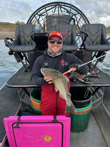 A man is standing on a boat holding a fish.
