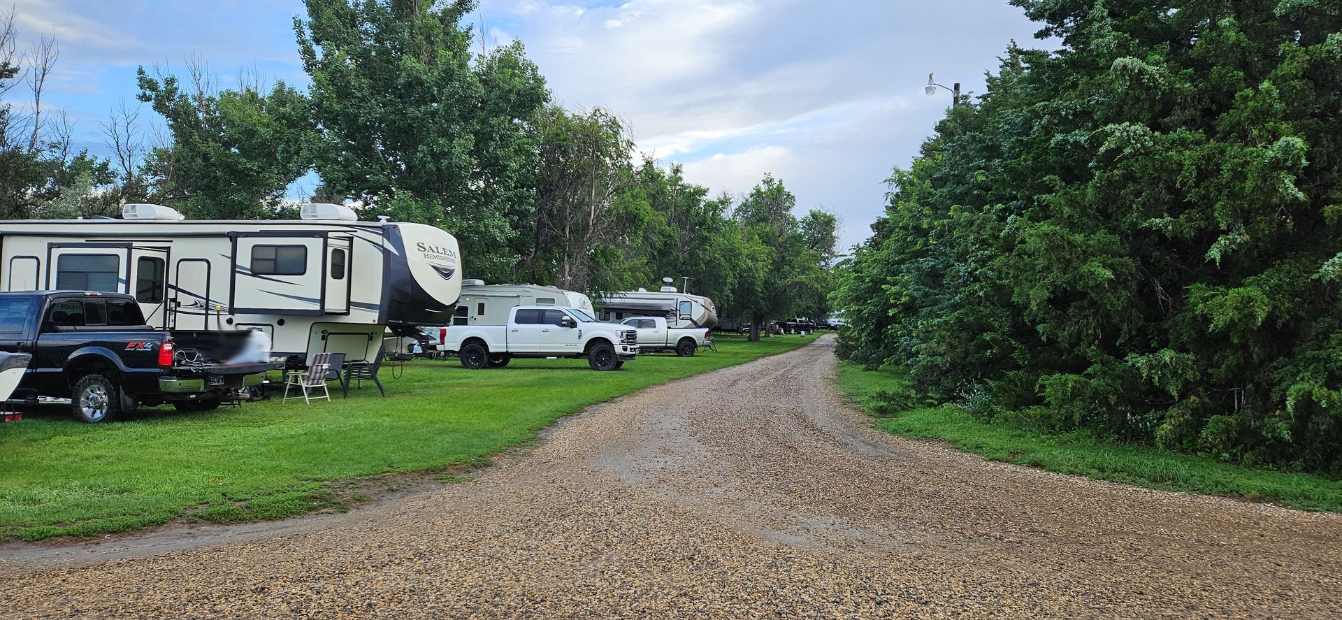 A dirt road with a lot of rvs parked on the side of it.