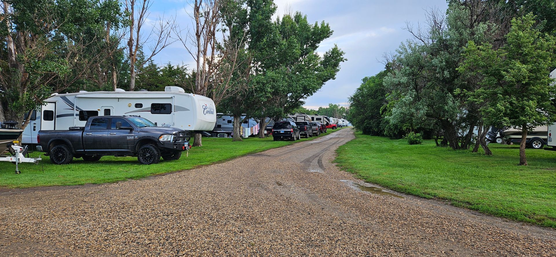 A truck is parked on the side of a gravel road next to a rv.