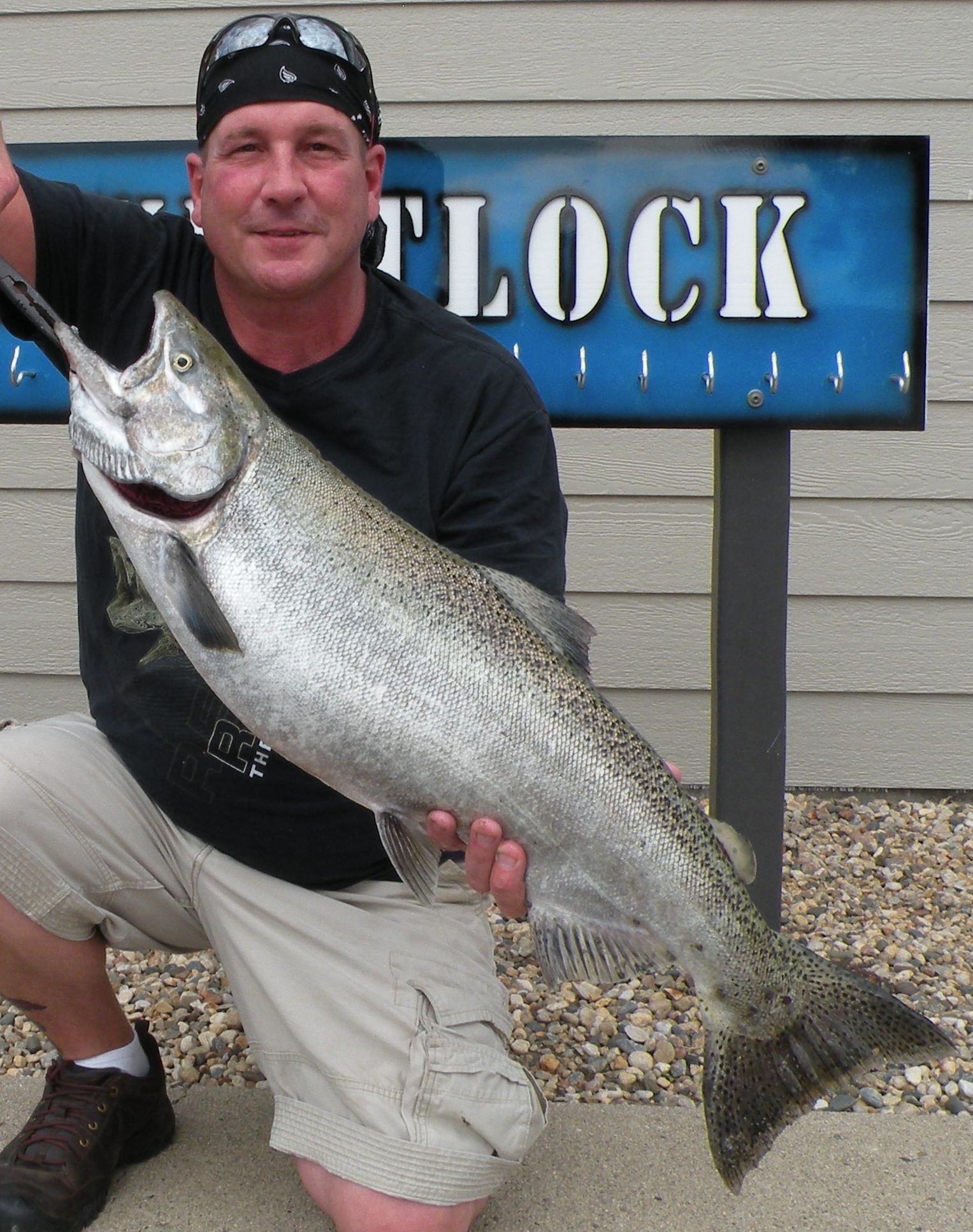 A man holding a large fish in front of a sign that says flock