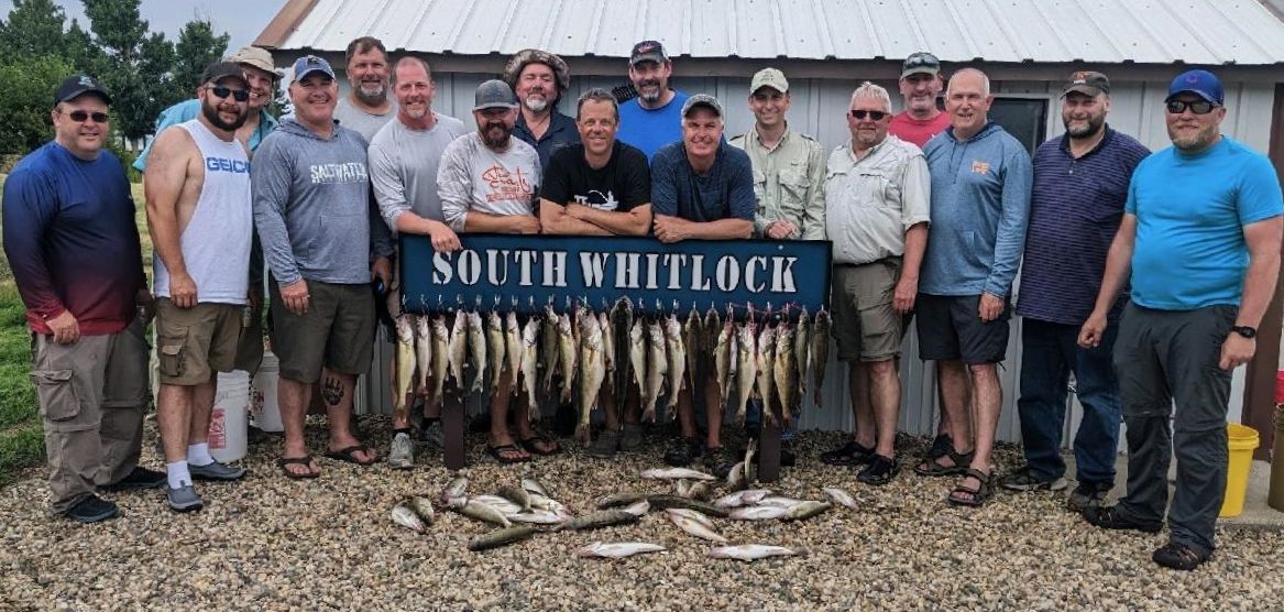 A group of men are posing for a picture in front of a sign that says south whitelock.