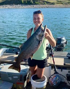 A woman is holding a large fish on a boat.