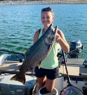 A woman is holding a large fish on a boat.