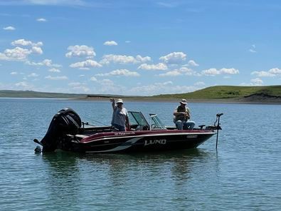 Two men are fishing in a boat on a lake.