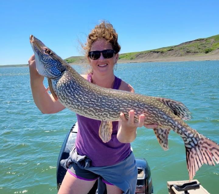 A woman on a boat holding a large fish