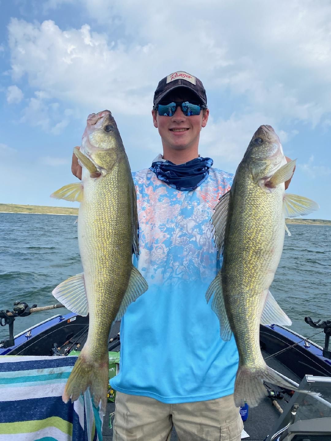 A man is holding two large fish on a boat.