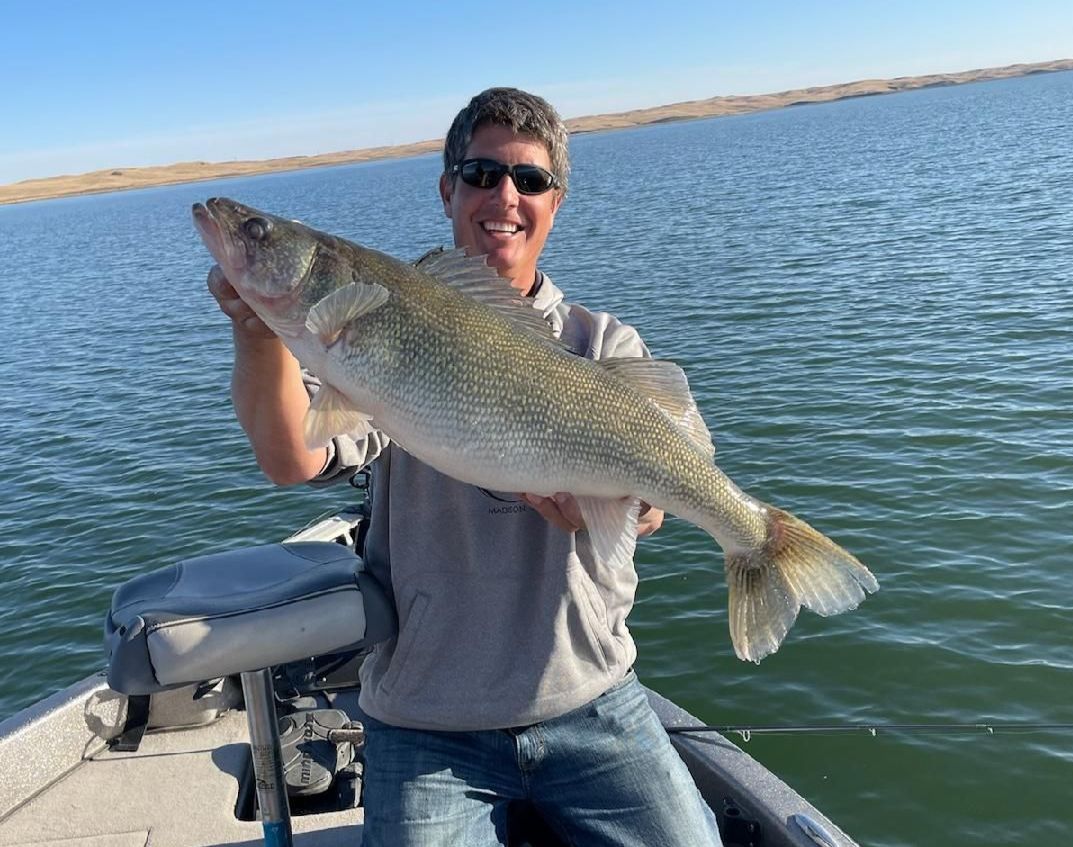 A man is sitting on a boat holding a large fish.