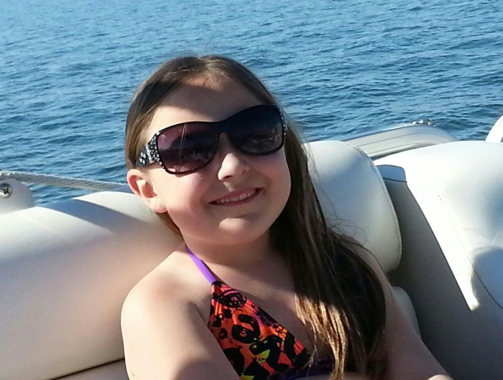 A young girl wearing sunglasses is sitting on a boat