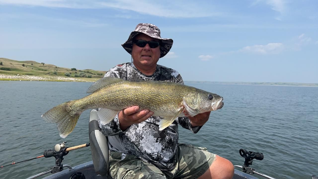 A man is sitting in a boat holding a large fish.