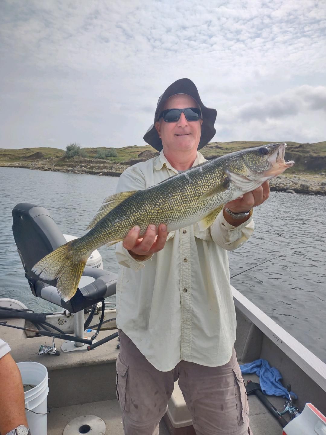 A man is holding a large fish on a boat.