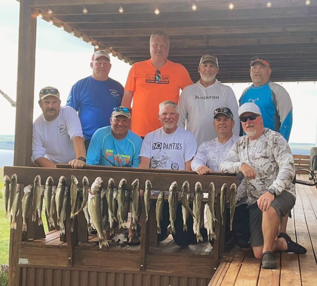 A group of men are posing for a picture in front of a display of fish.