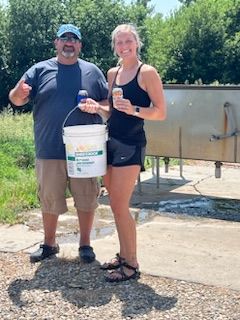 A man and a woman are standing next to each other holding buckets.