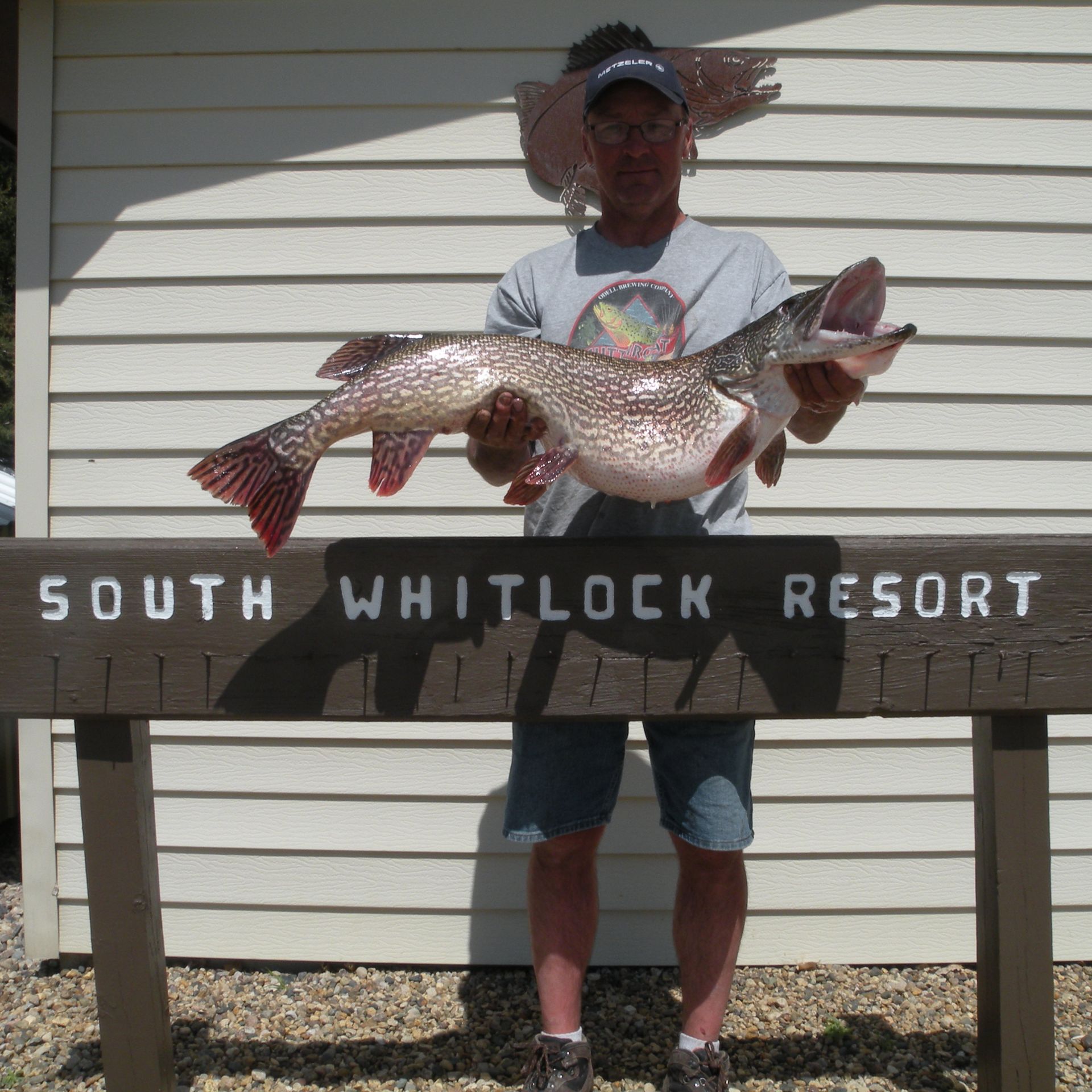 A man holding a large fish in front of a sign that says south whitlock resort