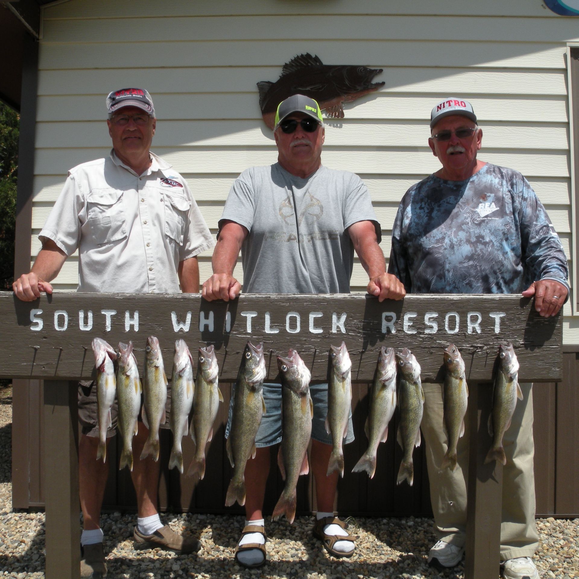Three men standing behind a sign that says south whitlock resort