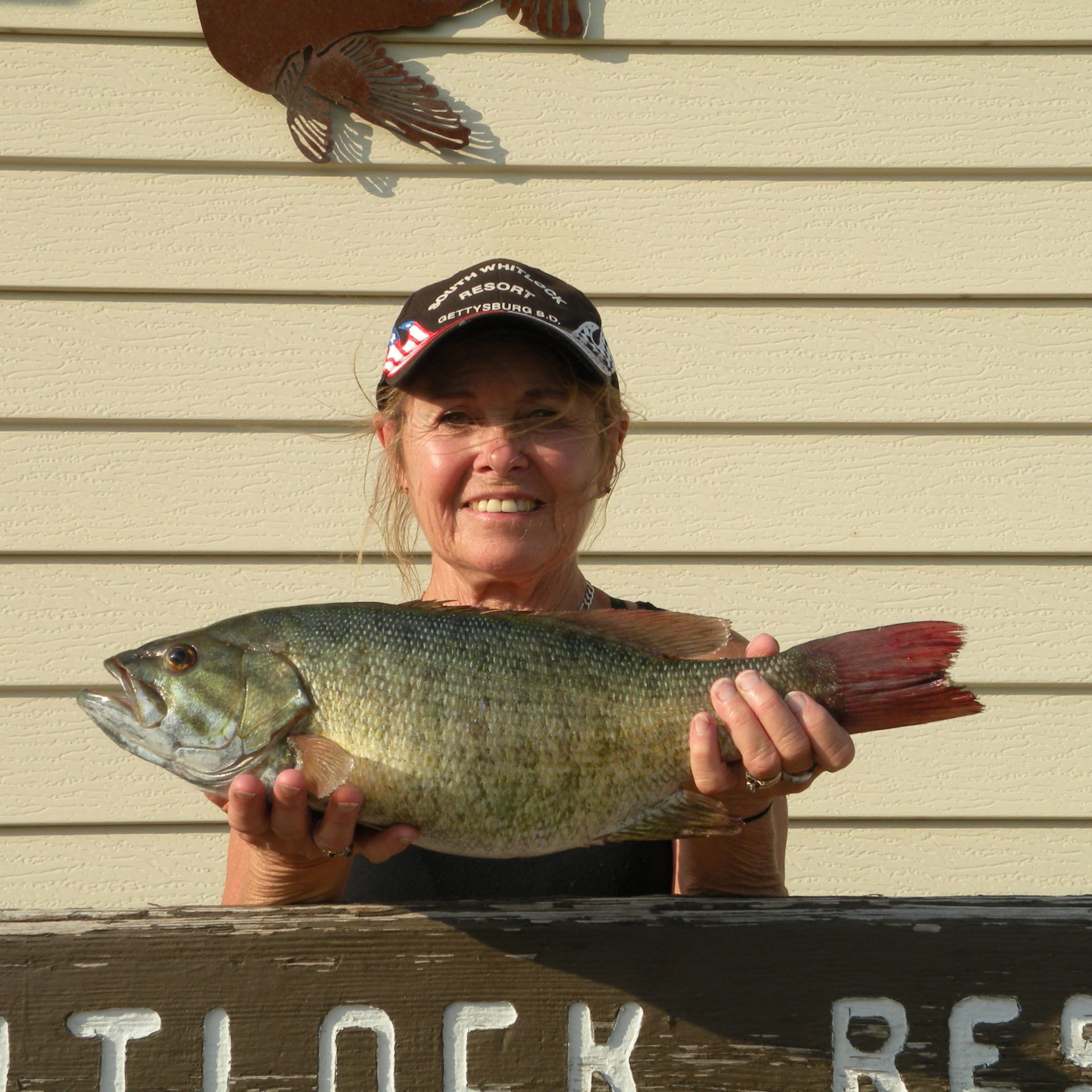 A woman is holding a large fish in front of a sign that says outlock resort