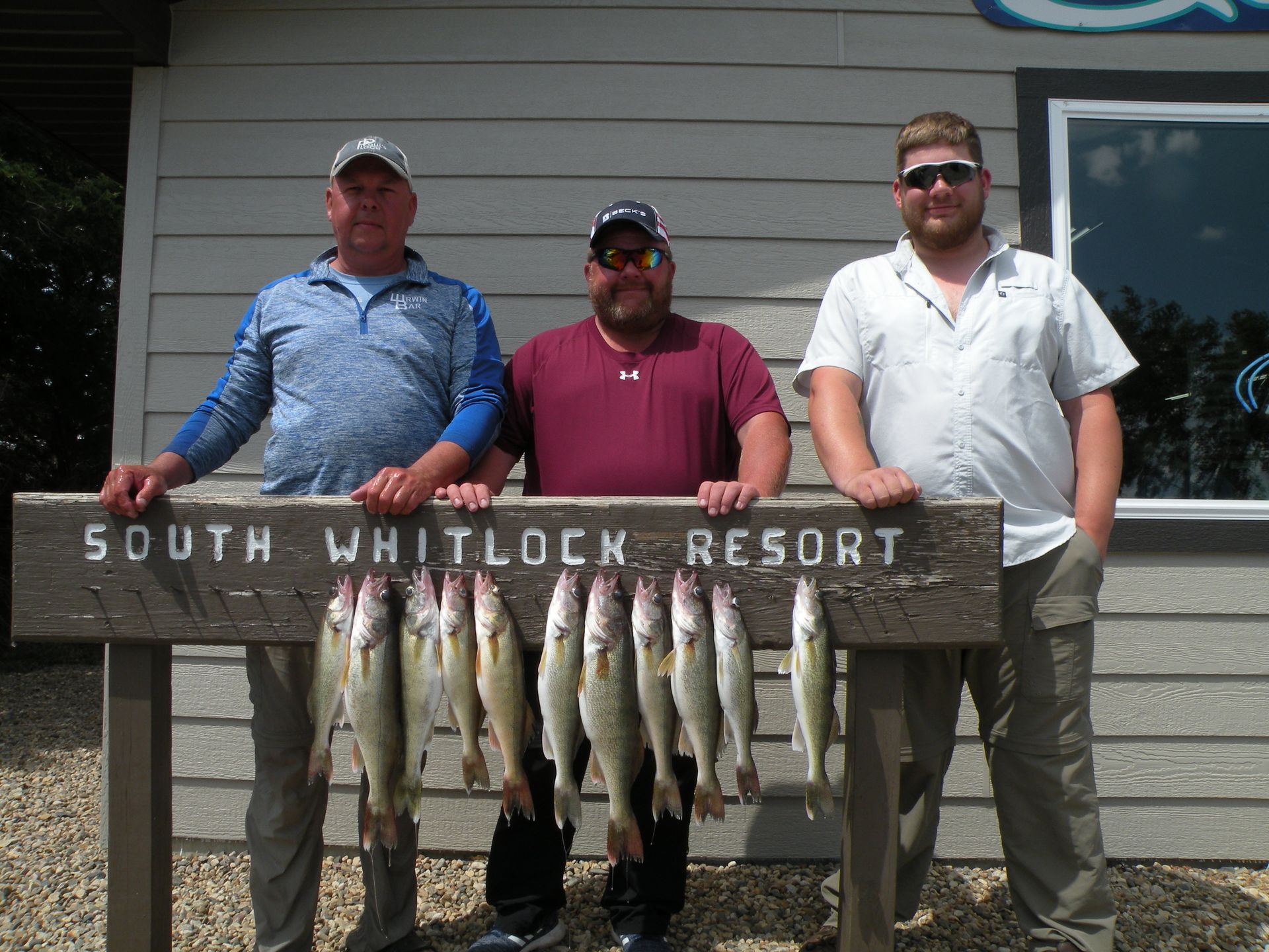 Three men standing next to a sign that says south whitlock resort