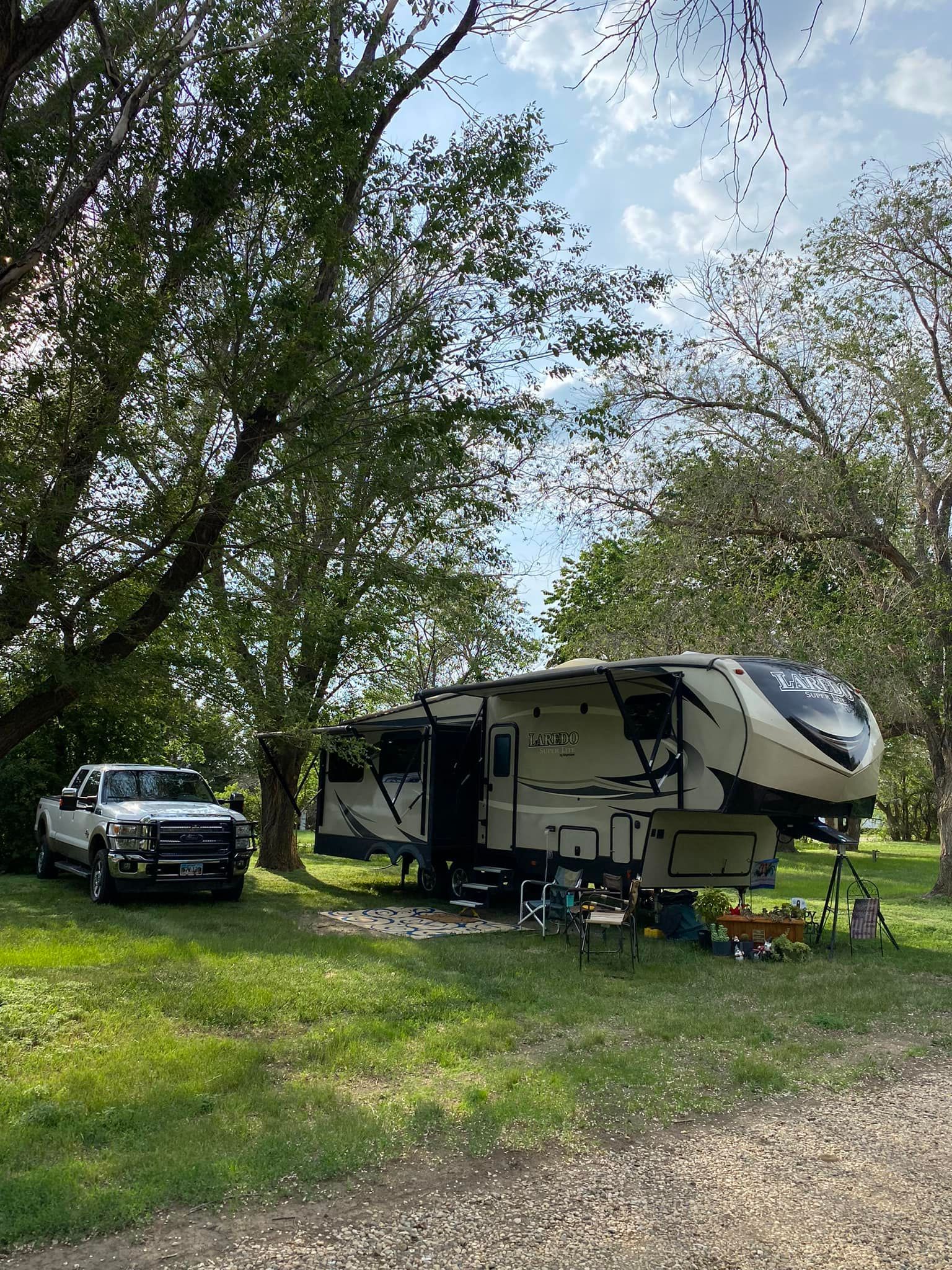A rv is parked in a grassy field next to a truck.