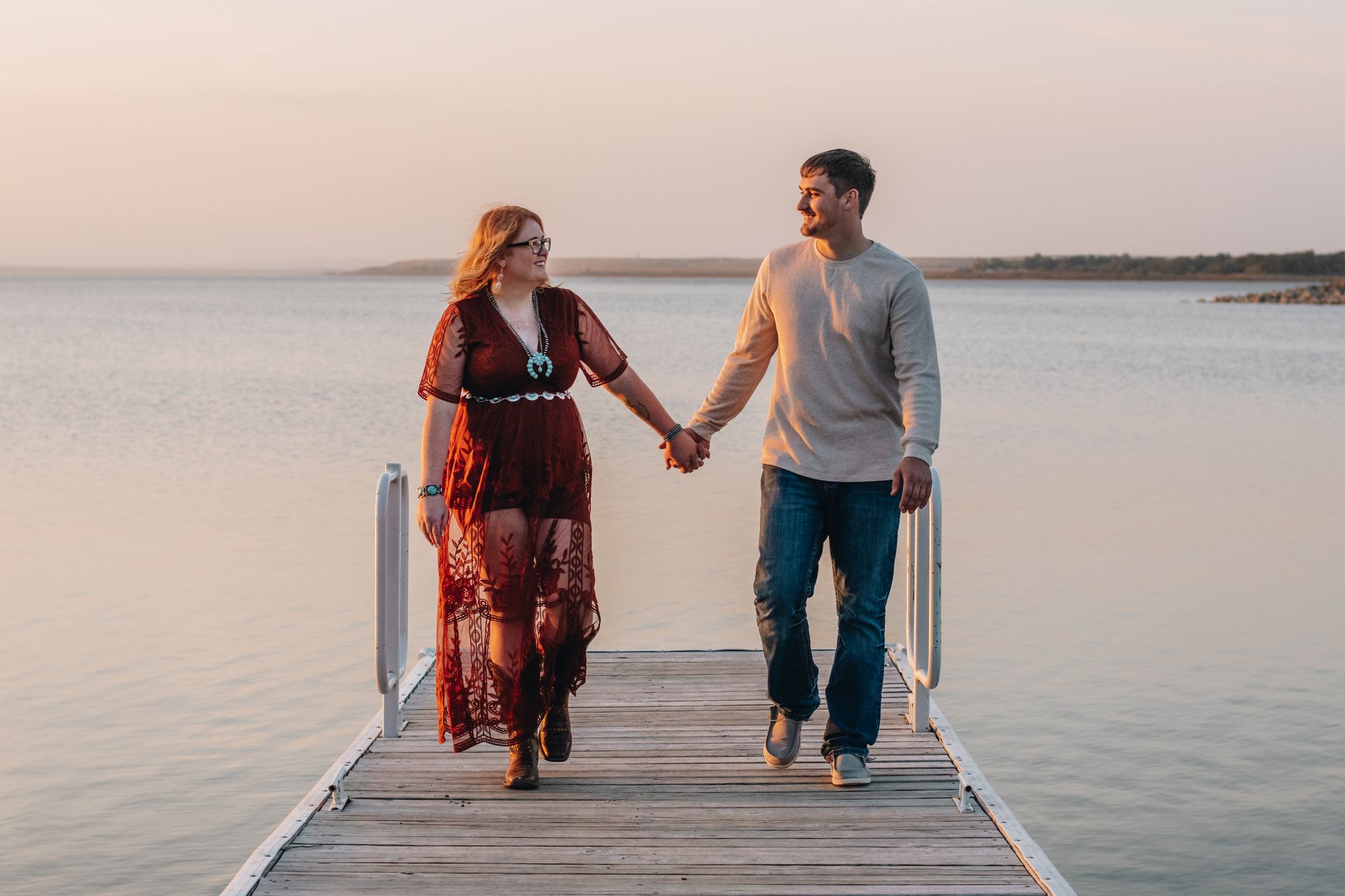 A man and a woman are walking on a dock holding hands.