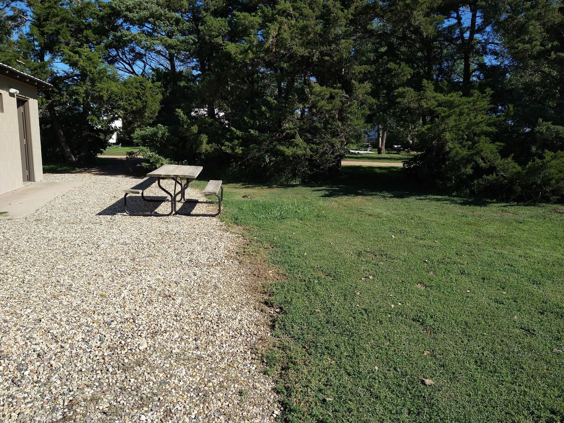 A gravel driveway with a picnic table in the middle of it.