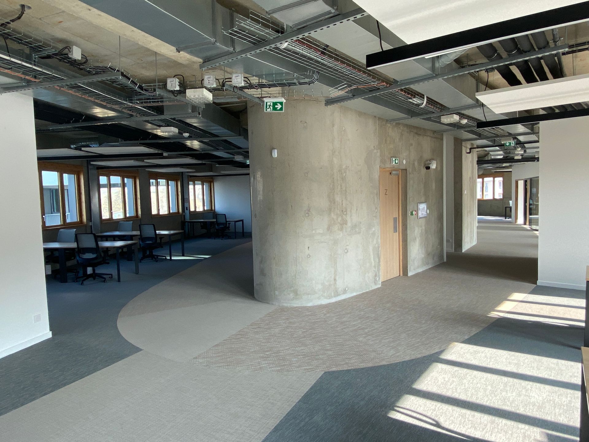Intérieur de bureau ouvert avec plafond apparent, colonne en béton, moquette au sol 