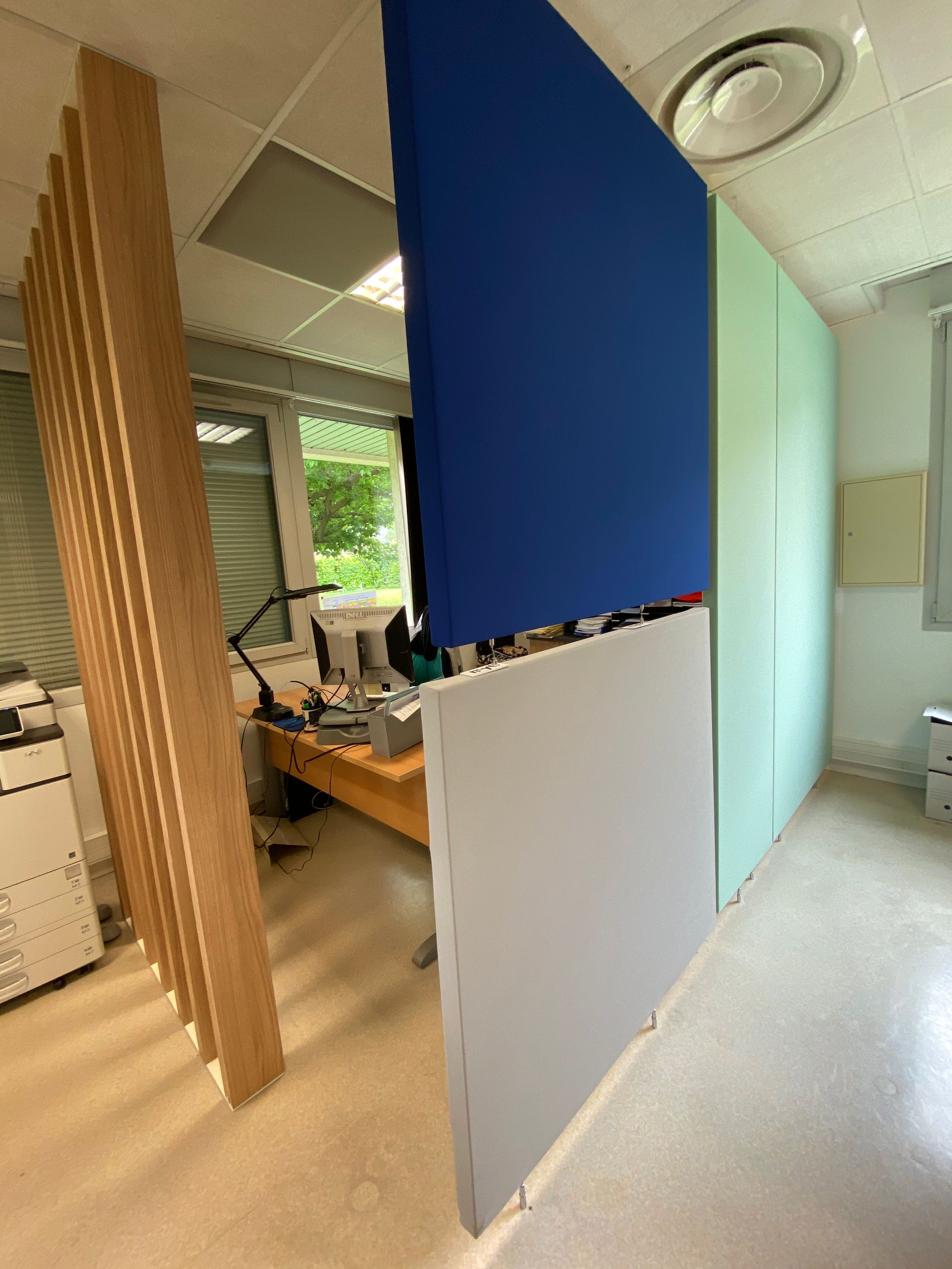 Intérieur de bureau avec des panneaux de séparation bleus et blancs et des lattes de bois à côté des bureaux et des fenêtres