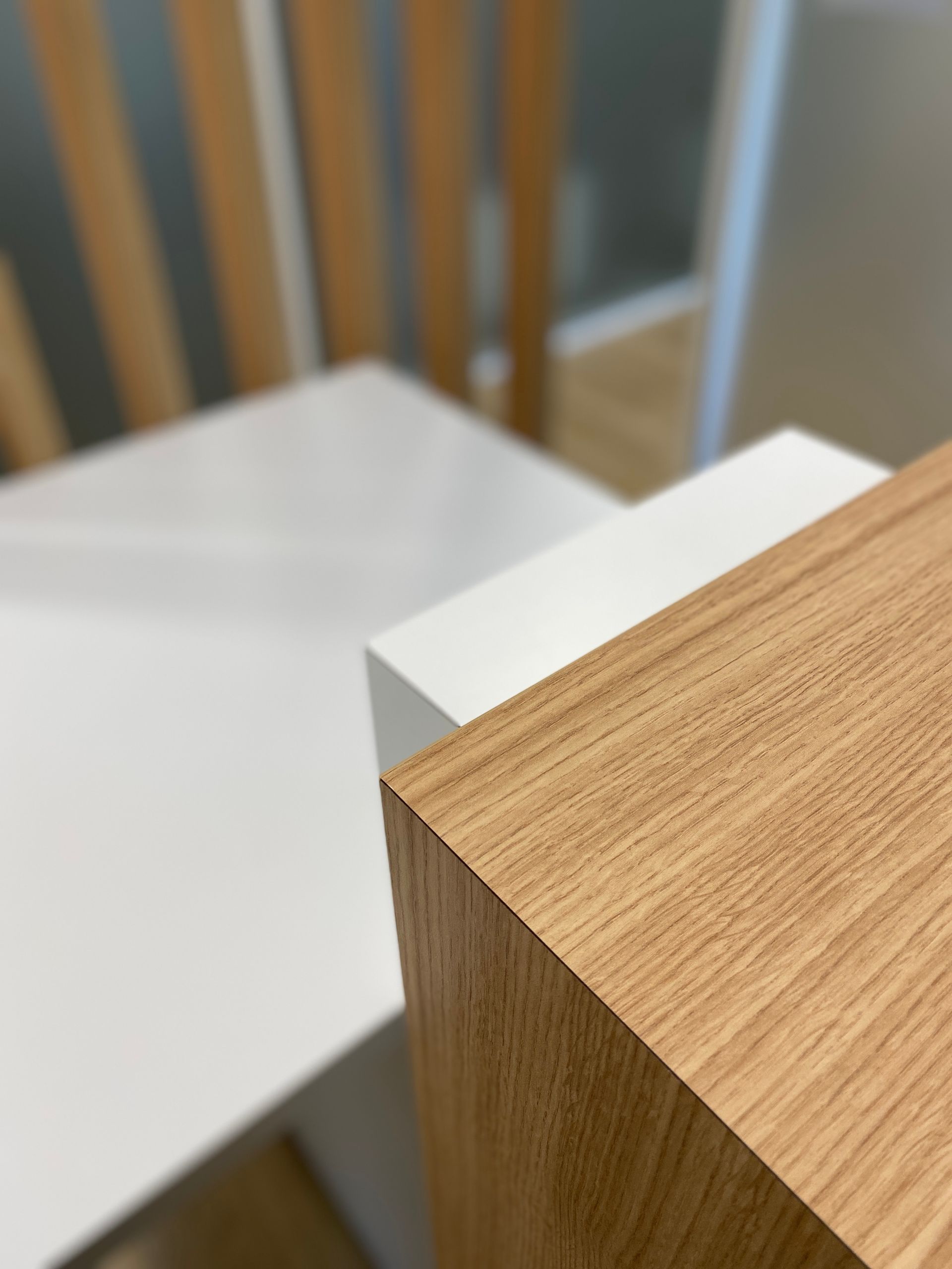 Coin de plateau en bois sur une table blanche avec des dossiers de chaises flous en arrière-plan
