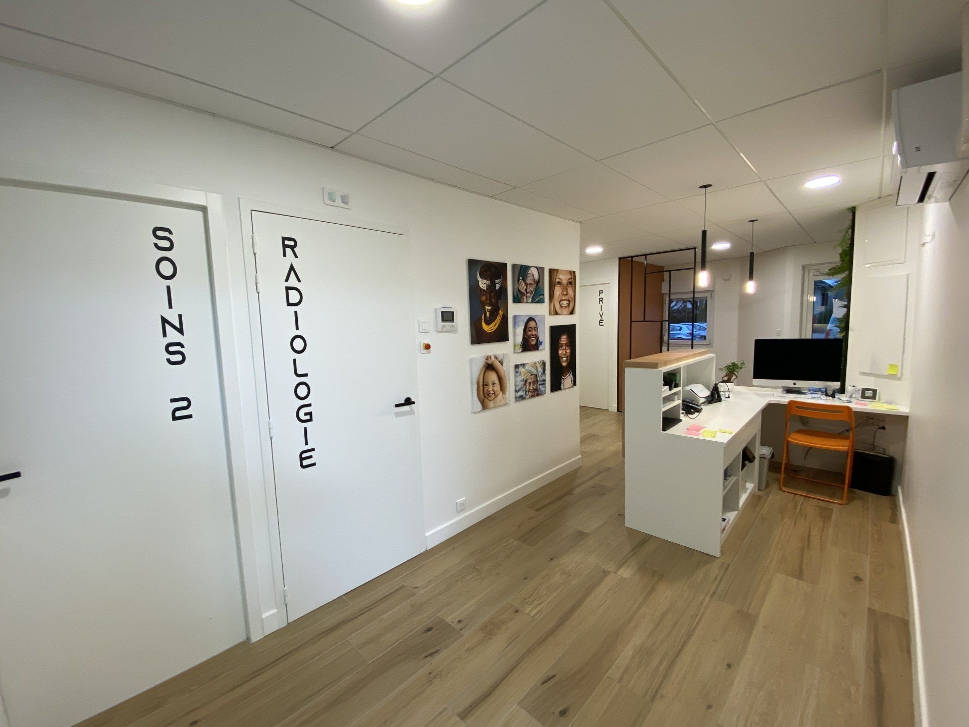 Intérieur de bureau lumineux et blanc avec parquet, bureaux, décorations murales et portes étiquetées le long du couloir