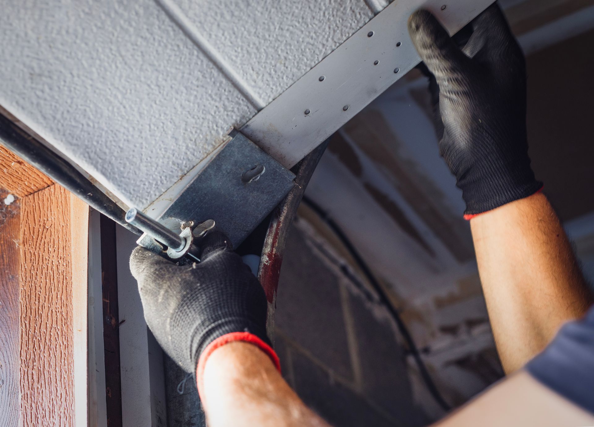 Worker tightening bracket on a garage door track.