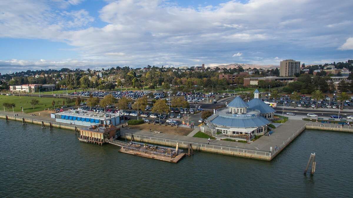 Aerial view of a waterfront marina with boats, a pier, and a blue-roofed pavilion by the water