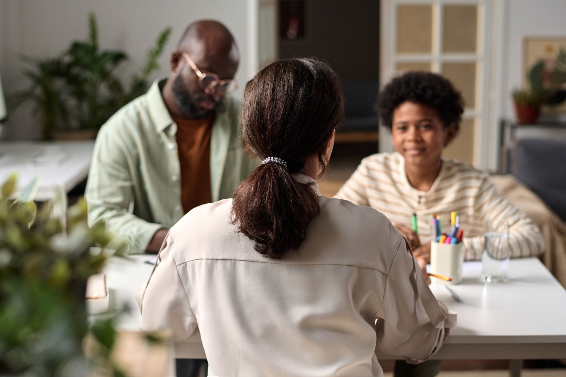 A woman is sitting at a table talking to a man and a boy.