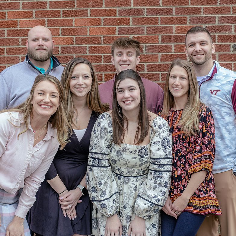 A group of people are posing for a picture in front of a brick wall.