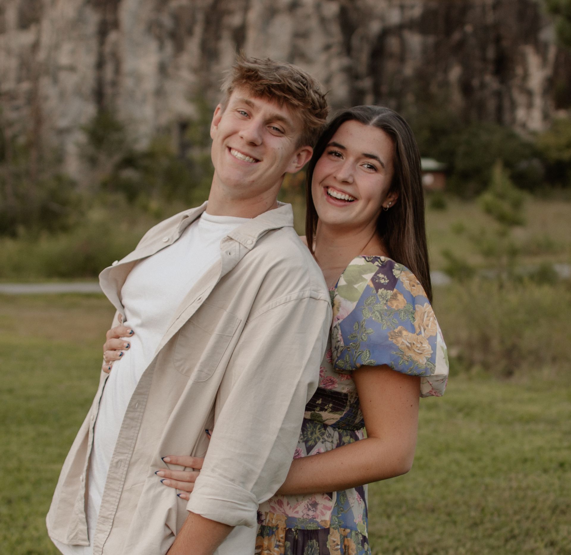 A man and a woman are posing for a picture and smiling for the camera.