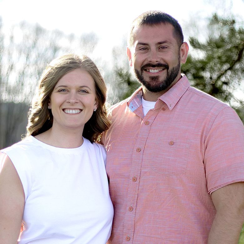 A man and a woman are posing for a picture and smiling for the camera.